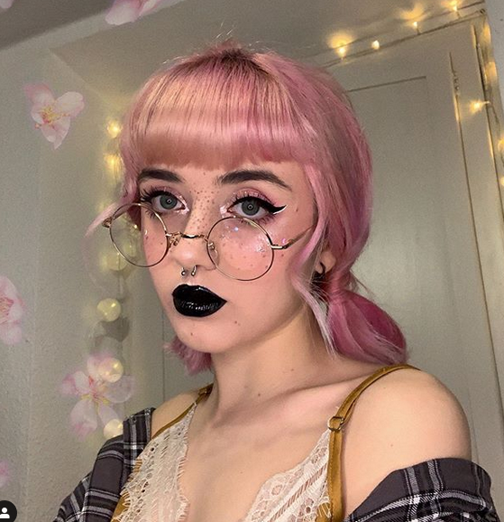 Young lady with light pick hearing wearing round wire rim glasses