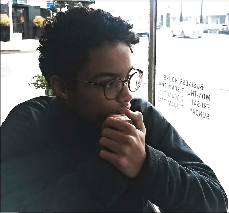 Young man wearing black round glasses looking out the window