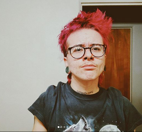 young man with red hair wearing tortoise round glasses